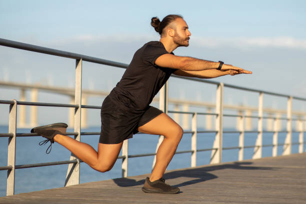 istock guy in activewear doing single leg lunge exercising at pier 2059031852
