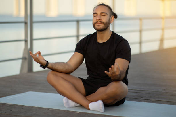 istock Calm sporty guy practicing yoga in lotus position meditating outside 2059032409