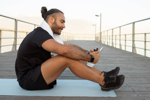 istock Man in activewear browsing sporty apps on phone sits outside 2059037924