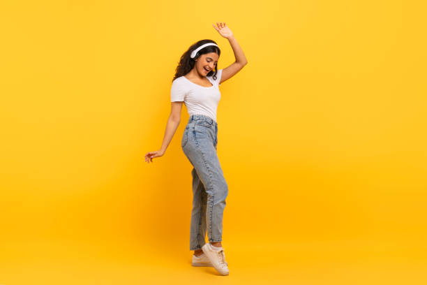 istock Overjoyed young indian woman using headphones and dancing 2059046985