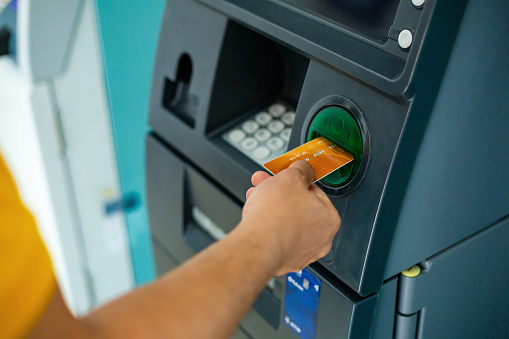 close up of man hand using ATM machine to withdraw money