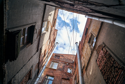 View from below of old square brick courtyard wall in St. Petersburg, Russia. Wall, windows and part of blue sky