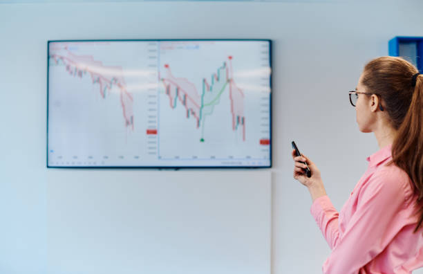 istock On Stage, Successful Female Speaker Presents Technological Product, Uses Remote Control for Presentation, Showing Infographics, Statistics Animation on Screen. Live Event Device Release 2059062999