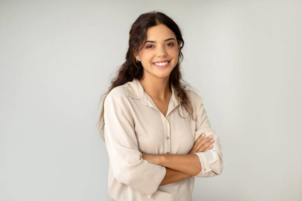 istock Smiling young woman standing confidently with arms crossed over light background 2059090943