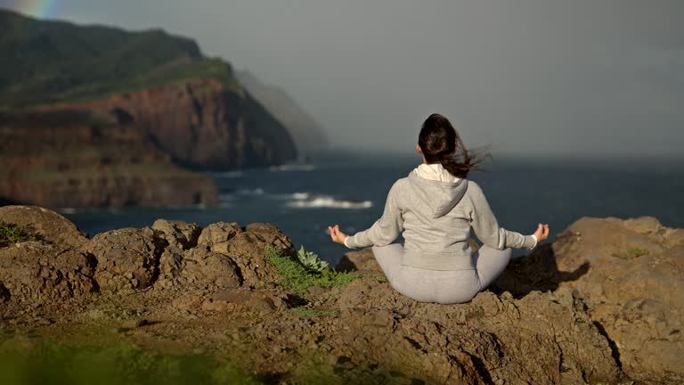 Yoga at sunrise with rainbow and wind turbines.