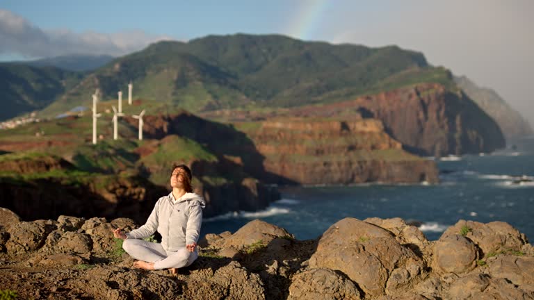 Yoga at sunrise with rainbow and wind turbines.