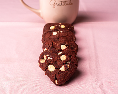 Heart-shaped cookies formed in a line and in the background a cup of pink coffee