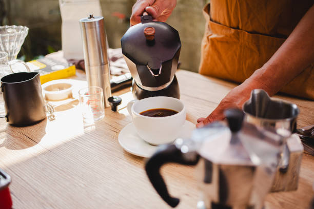 istock Close up hand Man using Italian classic Moka coffee pot pouring, coffee maker with equipment tool brewing table. 2059444716