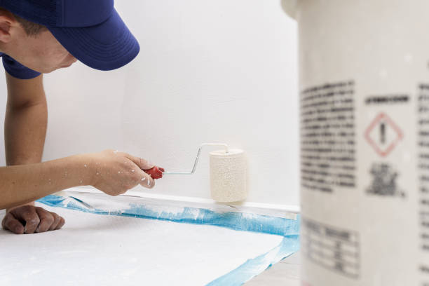 a man lying on the floor painting the wall of a house a man lying on the floor painting the wall of a house with white paint and with a roller in uniform house painting service stock pictures, royalty-free photos & images