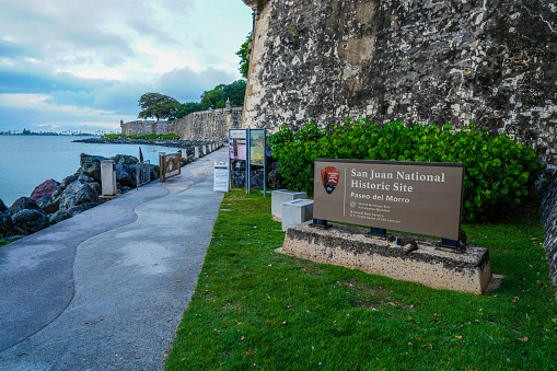 San Juan National Historic Site Paseo El Morro sign along the walkway under the imposing fortress wall of Old San Juan Puerto Rico