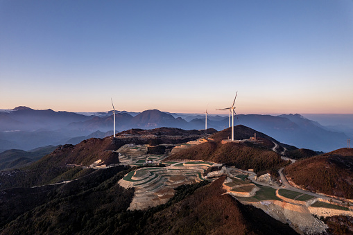 Terraced fields and wind turbines on the mountain at dusk