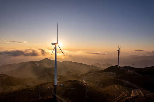 The clouds and mist on the high mountains and wind turbines at dusk