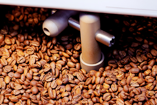 During roasting, coffee beans are prepared using oven machine for mixing raw coffee beans roasting them