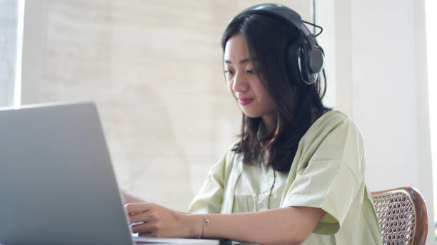 istock Young asian woman, digital nomad working remotely from a cafe, drinking coffee and using laptop, smiling. 2059658388