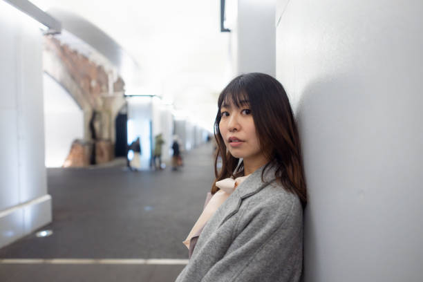 Business woman leaning on wall for waiting for someone after work