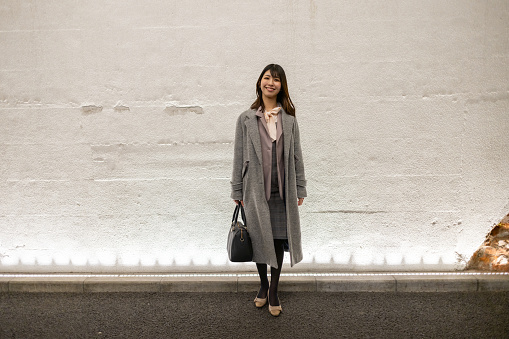 Fulll length portrait of business woman standing against white wall