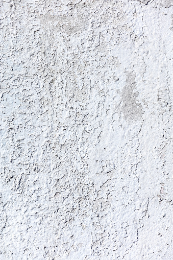 weathered shabby white plaster wall background with peeling off paint.
