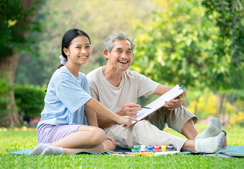 Portrait grandfather and granddaughter enjoy drawing in the park,family spend holiday time together