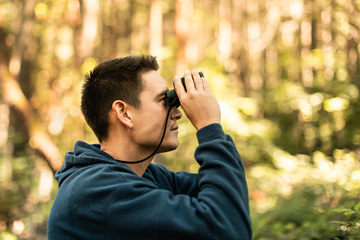Men looking through a binoculars in the forest.