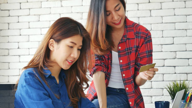 two friends shopping using credit card online shopping on website laptop e-commerce website with smiling face, happiness. happy asian women using laptop shopping online buy, payment newnormal concept - e commerce couple working at home internet zdjęcia i obrazy z banku zdjęć