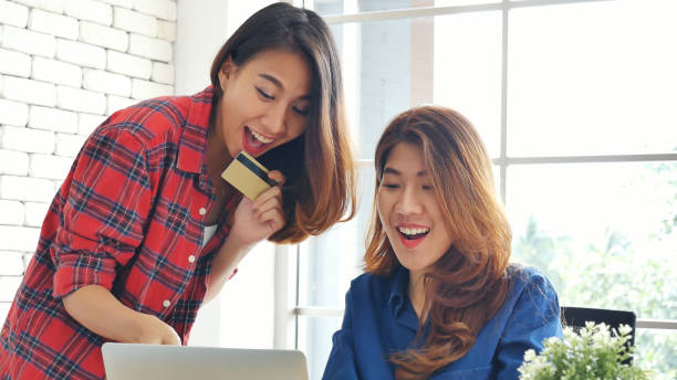 two friends shopping using credit card online shopping on website laptop e-commerce website with smiling face, happiness. happy asian women using laptop shopping online buy, payment newnormal concept - e commerce couple working at home internet zdjęcia i obrazy z banku zdjęć