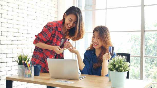 two friends shopping using credit card online shopping on website laptop e-commerce website with smiling face, happiness. happy asian women using laptop shopping online buy, payment newnormal concept - e commerce couple working at home internet zdjęcia i obrazy z banku zdjęć