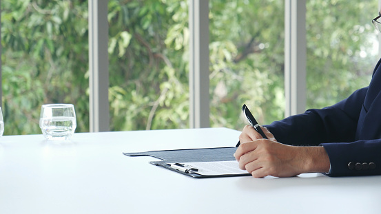 Businessman hands note meeting document in conference room. man Hands writing planning notebook. Close up male hand holding pencil write on diary sketchbook at office desk. Business Planning Concept