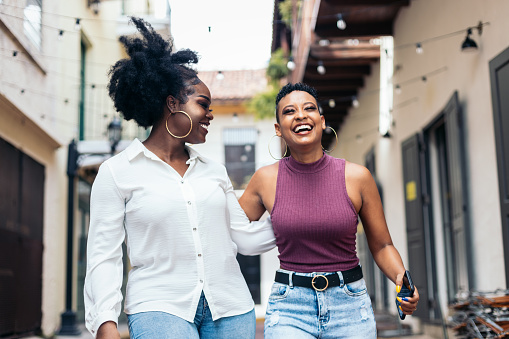 Stylish black women friends having fun and laughing a lot walking down the street
