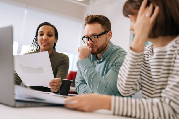 istock Pensive diverse group creative designers cooperating at office conference room sitting desk. Startup business team discussing work project at boardroom. 2059907073