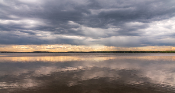 Blue lake with cloudy sky, natural background. Lake with forest on the shores at summer