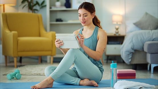 Fitness, internet and woman streaming on a tablet for training, yoga and exercise on the floor of her house. Happy, young and wellness girl with technology for a workout, cardio or video on pilates