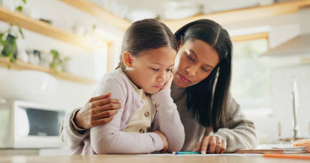 istock Homework, help and mother with girl in a kitchen for education, studying and remote learning project. Study, knowledge and mom with kid and book for reading, child development or homeschool lesson 2059988176