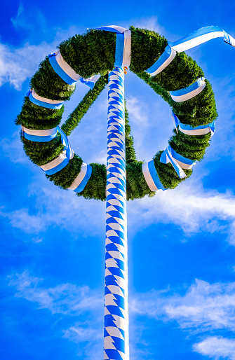 typical bavarian maypole in front of blue sky - photo