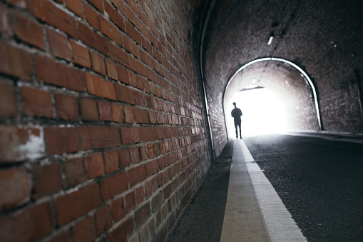 Image of brick wall tunnel and people silhouette