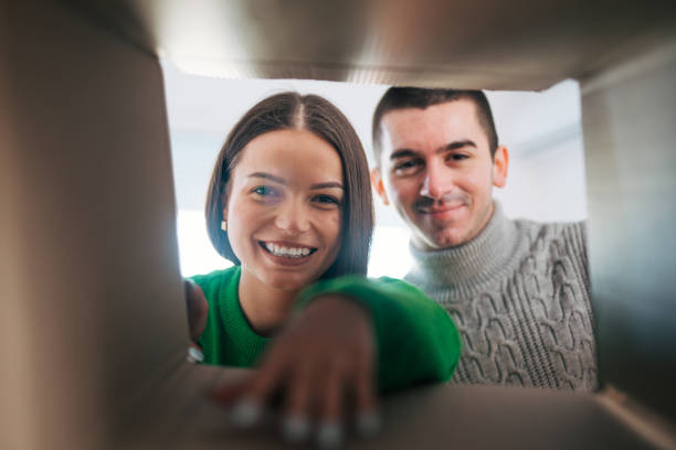 istock Smiling young couple opening a carton box and looking inside. 2060023907