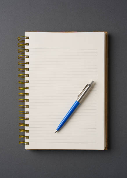istock Ballpoint pen made of blue plastic and metal standing on lined notebook 2060026133