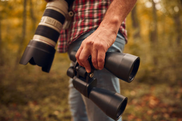 istock Man using binoculars and camera for birdwatching and other observing animals in nature. 2060026155