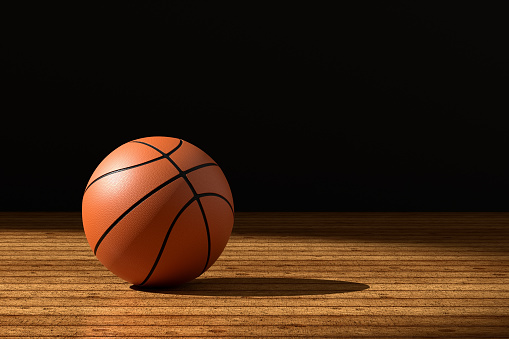 Basketball on weathered wooden court floor under the spotlight. Basketball game, sports, match and competition concept. 3D render.