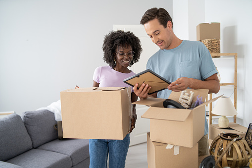 Young couple family with boxes to move in a new house room