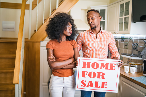 African couple having problems, woman holding a sign for sale