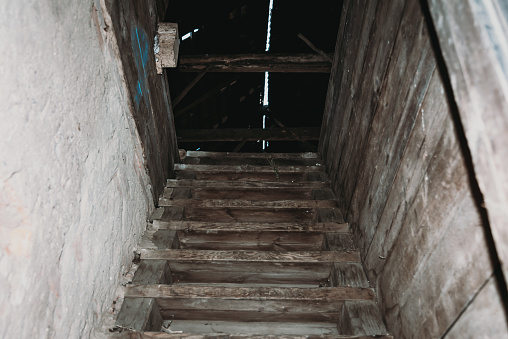 Old dirty damaged wooden stairs to the garret.Entrance to the attic.Stairs up,dusty dark stairs.