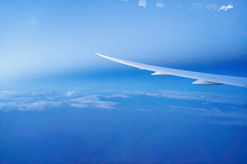 Airplane wing seen from inside the craft, clear blue sky above the clouds