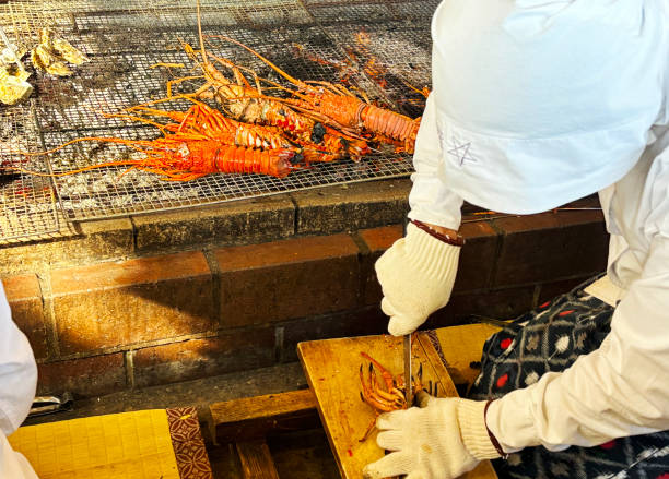 ama plongeur a coupé une langouste grillée au charbon de bois avec un couteau.    préfecture de mie, japon - gourmet food lobster seafood photos et images de collection