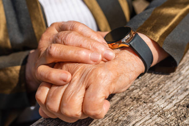 elderly woman with smart watch fitness band checking her pulse,outdoors on the old wooden table,sumer sunny day. closeup. - 11873 - fotografias e filmes do acervo