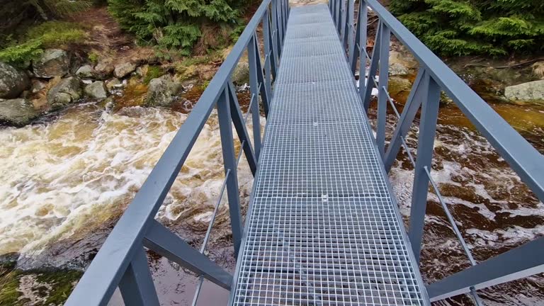 raging elements of water in a mountain river. the damaged and torn down wooden mast was washed away by the flood and crushed against the rocks. the new metal durable bridge withstands the waves of the