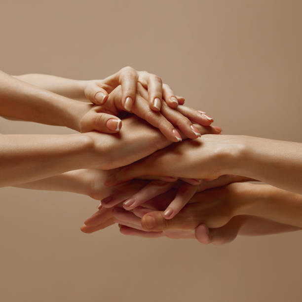 istock Various woman puts his hands together showcasing unity, teamwork and support against beige studio background. 2060109071