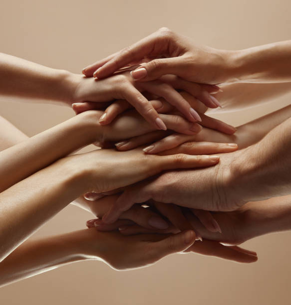 istock Various woman puts his hands together showcasing unity, teamwork and support against beige studio background. 2060109598