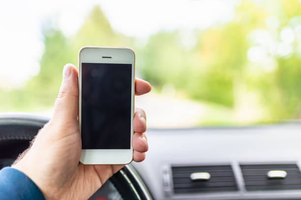 Mans hand hold and touch screen smart phone, blur on the road high way forest summer background.copy space,advertisement,banner,mockup.