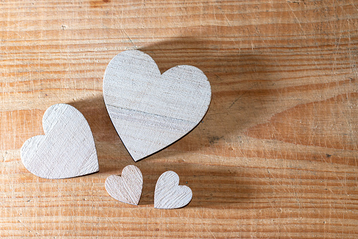 Four wooden hearts of different sizes flat lay on a brown wooden background. Love, family and Valentine's Day concept.Copy space.
