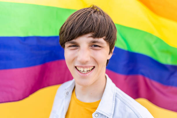 istock Young gay man smiling at camera over rainbow flag background. 2060113551